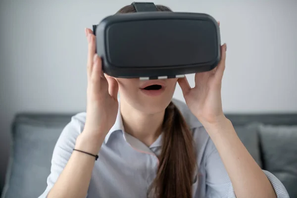 Förbluffad dam sitter i ett rum och spelar ett 3D-spel — Stockfoto