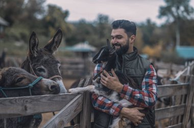 Sevimli bir keçi yavrusu tutan mutlu bir çiftçi.
