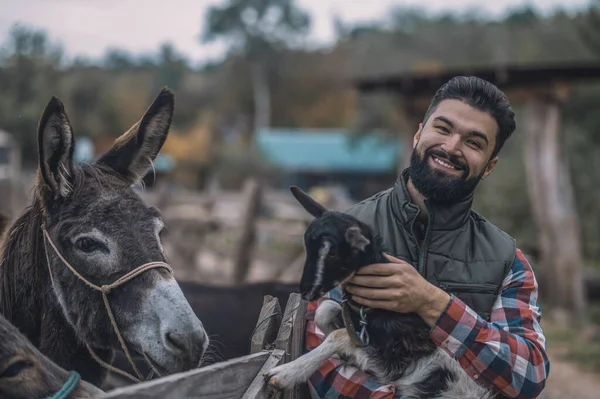 Egy boldog gazda, aki egy aranyos kecskét tart. — Stock Fotó