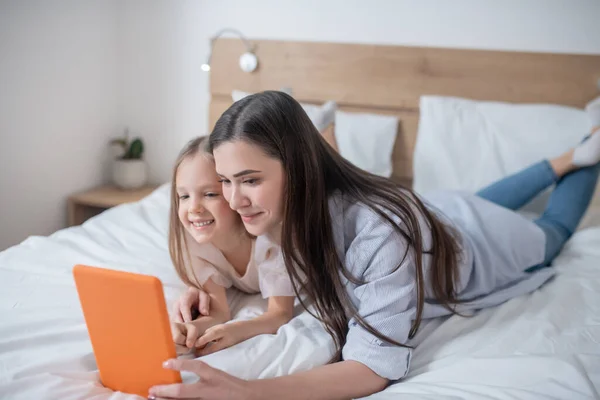 Moeder vermaken haar vrouwelijke kind met behulp van een mobiel apparaat — Stockfoto