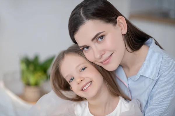 Glückliche Mutter und ihre fröhliche Tochter posieren für die Kamera — Stockfoto
