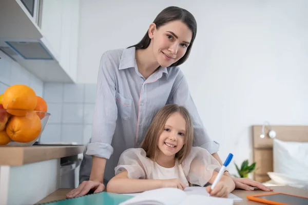 Kind doet huiswerk geholpen door haar moeder — Stockfoto