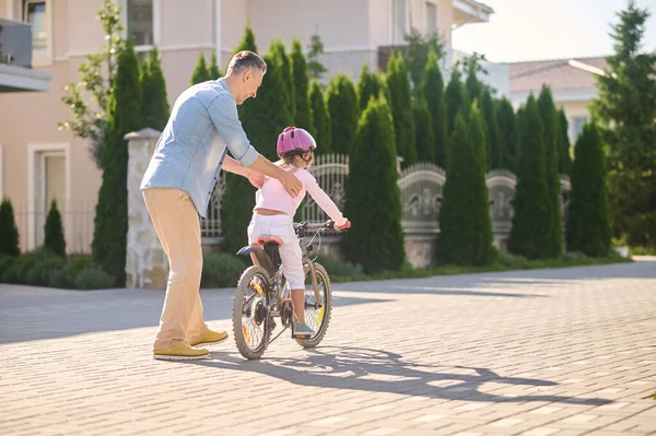 Papá ayudando a su hija a aprender a montar en bicicleta — Foto de Stock