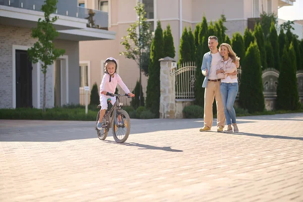 両親が彼女を見ている間に自転車に乗っている女の子 — ストック写真