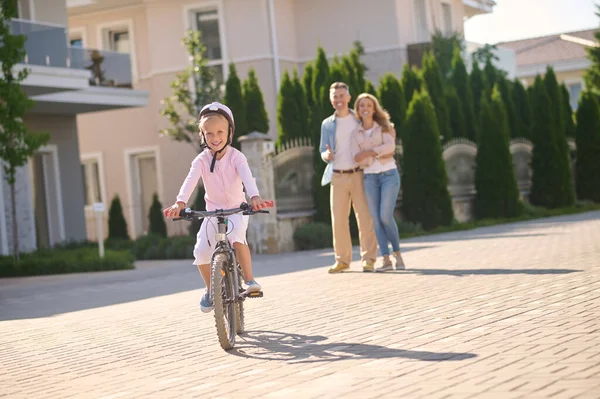 Une fille en vélo pendant que ses parents la regardent — Photo
