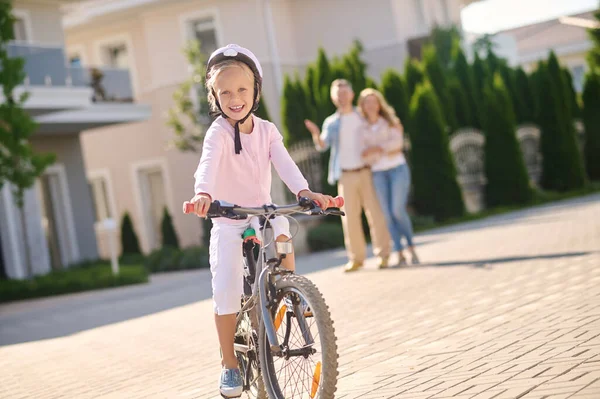 Une jolie blonde apprenant à faire du vélo avec ses parents — Photo