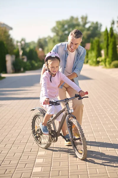 Un hombre apoyando a una chica mientras monta en bicicleta — Foto de Stock