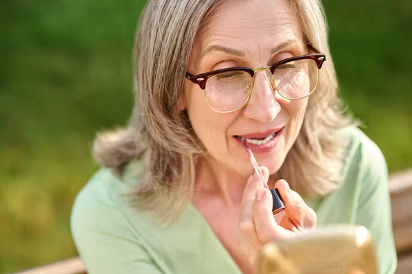 Mulher feliz pintando lábios ao ar livre — Fotografia de Stock