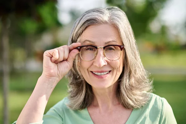 Donna che tocca gli occhiali guardando la fotocamera — Foto Stock
