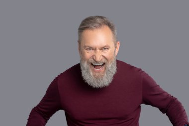 Burgonya gömlekli olgun bir adam heyecanlı görünüyor.