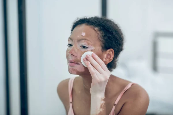 A pretty young woman cleansing her face with a sponge