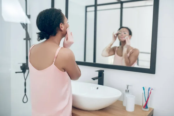 Женщина в розовом белье в ванной комнате во время процедуры красоты — стоковое фото