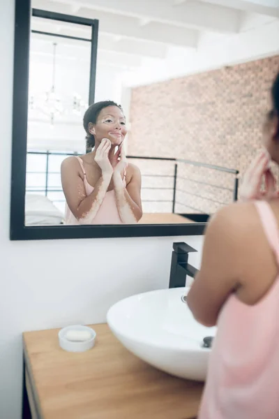 Kobieta w różowej bieliźnie w łazience podczas zabiegów kosmetycznych — Zdjęcie stockowe
