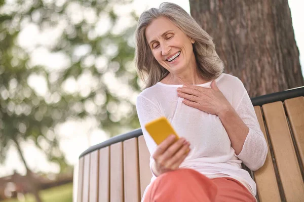 屋外のスマートフォンの画面を見て話す女性 — ストック写真