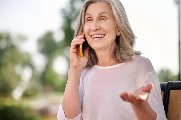 Frau hält Smartphone am Ohr und spricht — Stockfoto