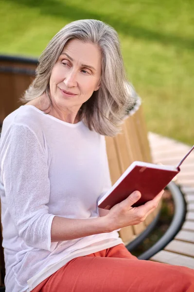 Mulher meditativa com livro sentado no banco — Fotografia de Stock