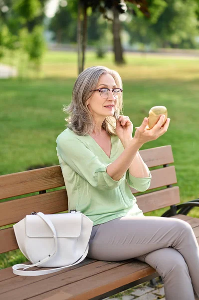 Woman looking in mirror sitting on bench — Stock Photo, Image