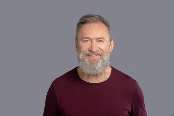 Rijpere man in bordeaux shirt ziet er positief uit — Stockfoto