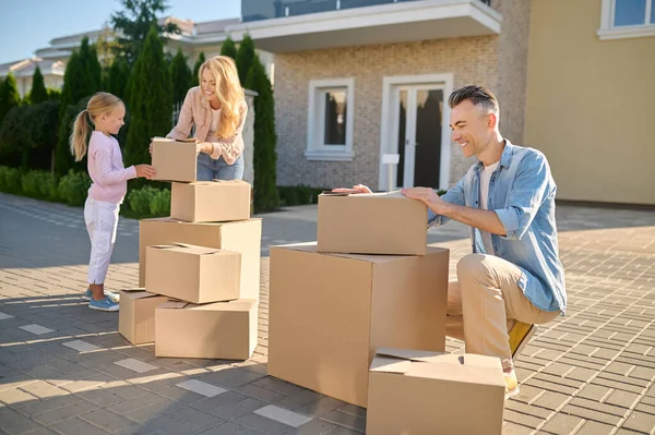 Familia mudándose a una casa nueva y llevando cajas de cartón — Foto de Stock