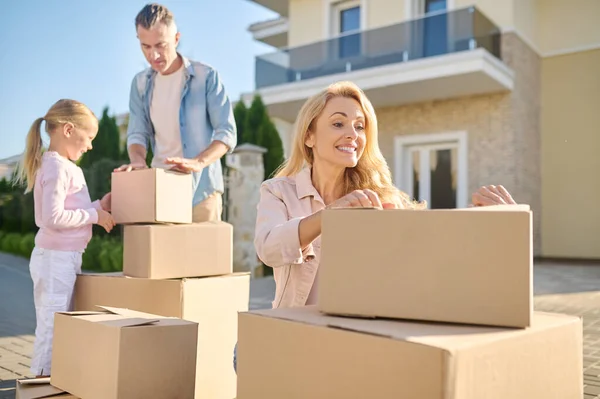 Familia mudándose a una casa nueva y llevando cajas de cartón — Foto de Stock