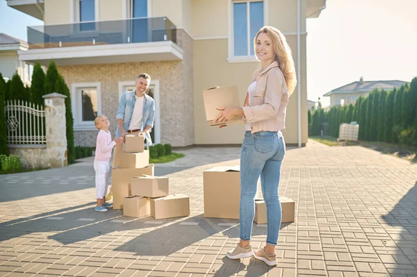 Familia mudándose a una casa nueva y llevando cajas de cartón — Foto de Stock