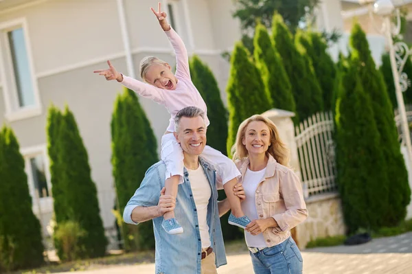 Papai carregando uma menina em seus ombros durante a caminhada da família — Fotografia de Stock