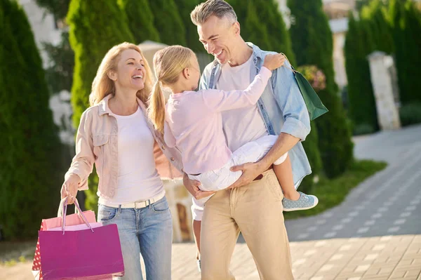 Familia que regresa de las compras y lleva bolsas de compras — Foto de Stock
