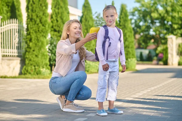 Mamá arreglando una mochila en la espalda de sus hijos — Foto de Stock