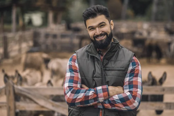 Um fazendeiro de colete preto e uma camisa xadrez em pé perto do gado-caneta — Fotografia de Stock