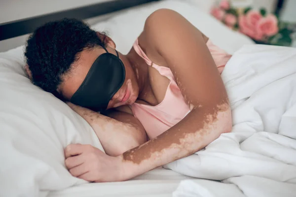 Seorang wanita muda bertopeng tidur di tempat tidur — Stok Foto