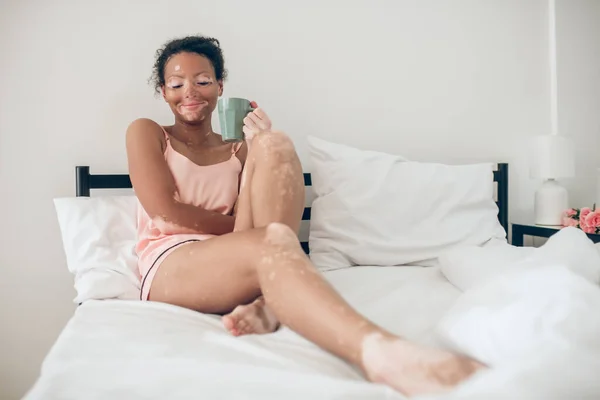 Een jonge vrouw genieten van haar ochtend kruidenthee en op zoek tevreden — Stockfoto