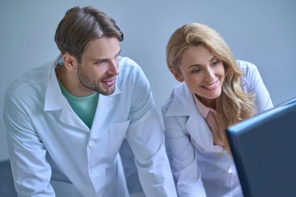 Mężczyzna i kobieta w białym płaszczu patrzący na komputer — Zdjęcie stockowe
