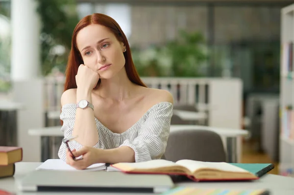 Mulher triste sentada à mesa com livros — Fotografia de Stock