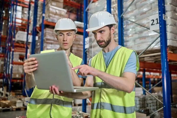Dois homens olhando para laptop decidir questão de trabalho no armazém — Fotografia de Stock