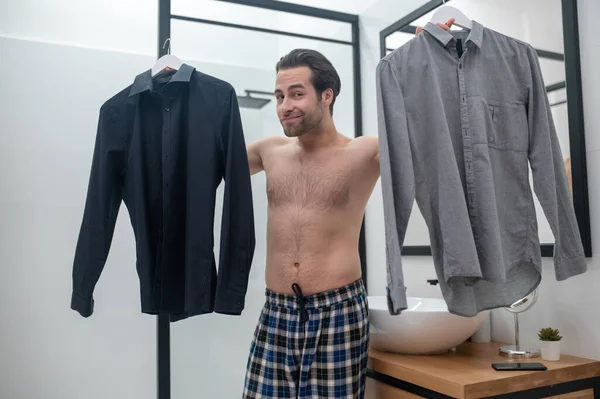 Hangi gömleği seçeceğine tereddüt eden bir adam.