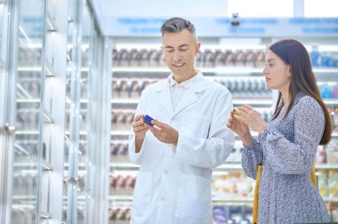 Erkek eczacı eczanede müşteriye danışıyor.