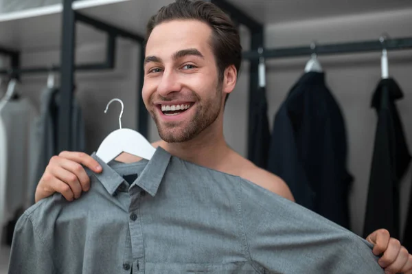 Man in plaid home pants choosing a shirt to wear — Stock Photo, Image