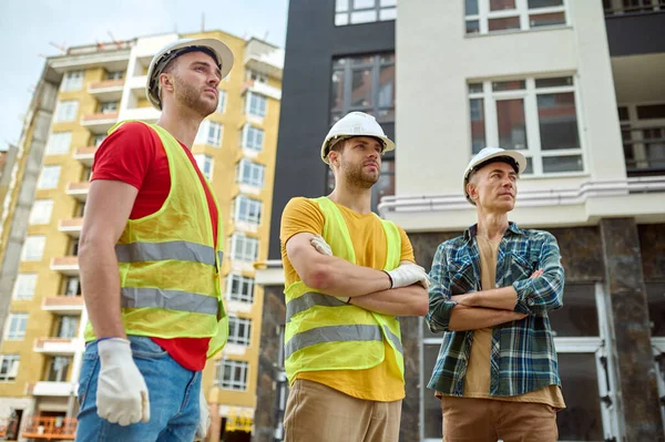 Három ember félrenéz az építkezésre. — Stock Fotó