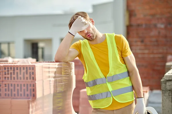 Tired worker touching face at construction site — Stock Photo, Image