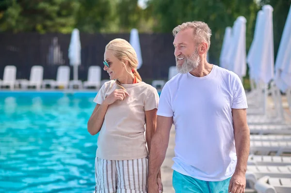 Een man en een vrouw die langs het zwembad lopen — Stockfoto