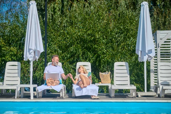 Deux personnes assises sur des chaises longues près de la piscine — Photo