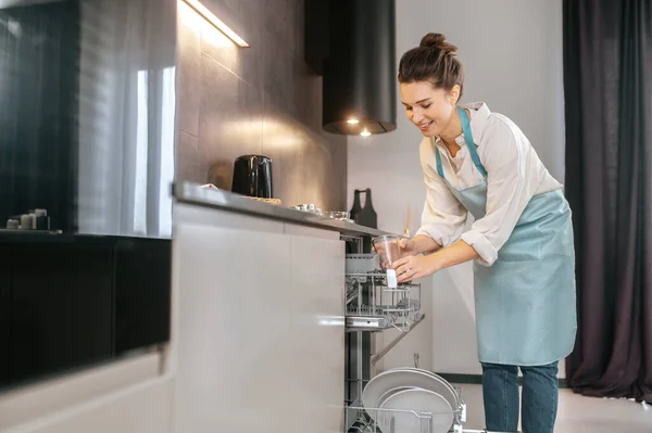 Νεαρή γυναίκα στην κουζίνα δείχνει απασχολημένη ενώ πλένει τα πιάτα. — Φωτογραφία Αρχείου