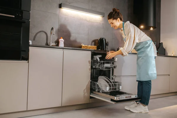 Jonge vrouw in de keuken op zoek druk terwijl het wassen van de borden — Stockfoto