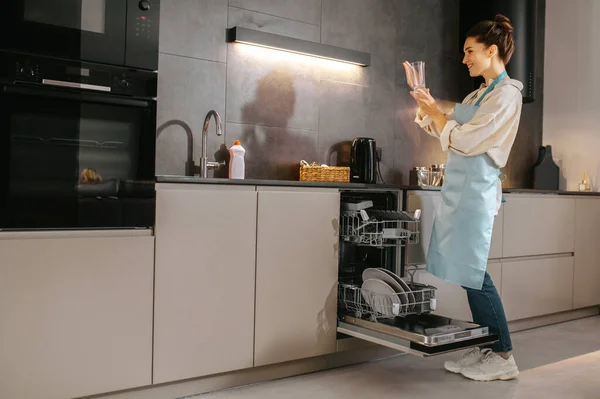 Mujer joven en la cocina buscando ocupado mientras lava los platos — Foto de Stock