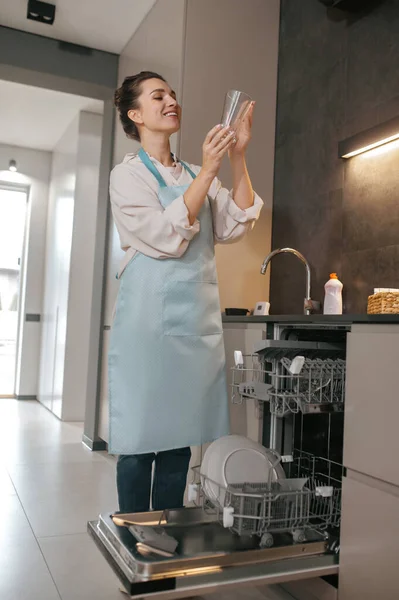 Jonge vrouw in schort schoonmaken van het servies — Stockfoto