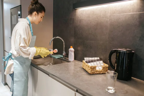 Жінка в жовтих рукавичках миє посуд — стокове фото