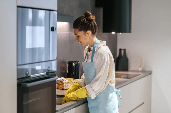 Ama de casa en delantal y guantes amarillos lavando los platos — Foto de Stock