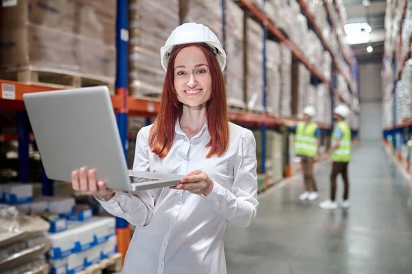 Dizüstü bilgisayarda çalışan kadın ve arkada çalışan işçiler.