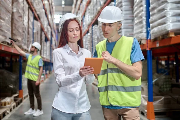 Donna che mostra tablet al lavoratore e collega dietro — Foto Stock