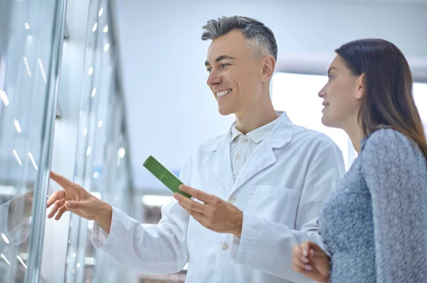 Especialista masculino consultando um cliente sobre produtos de cuidados com o corpo — Fotografia de Stock